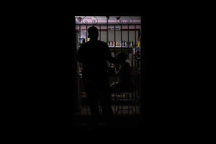 Archivo - Se ve la silueta de un habitante de La Habana frente a una pequeña tienda durante un apagón generalizado que afecta a la capital cubana.