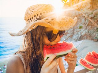 Archivo - Mujer en la playa en verano comiendo sandía.