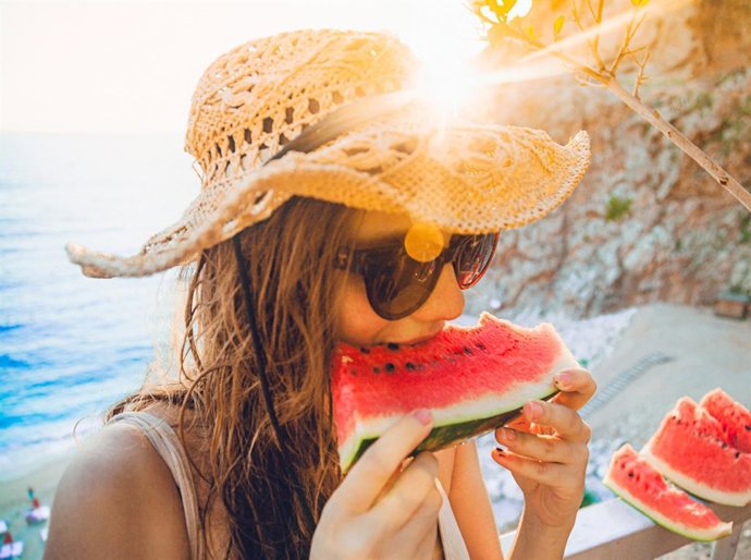 Archivo - Mujer en la playa en verano comiendo sandía.