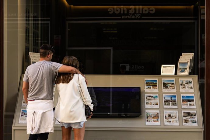 Archivo - Dos personas observan los anuncios de viviendas en venta en una inmobiliaria.