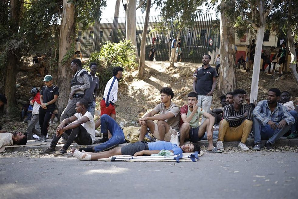 Varias personas esperan a las puertas del Centro de Estancia Temporal de Inmigrantes (CETI), a 2 de agosto de 2026, en Ceuta (España).