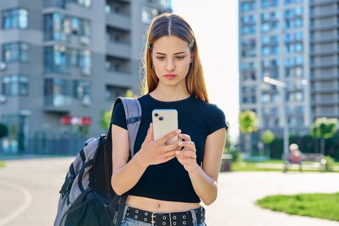 Archivo - Arquivo - Garota olhando para o celular com expressão séria.
