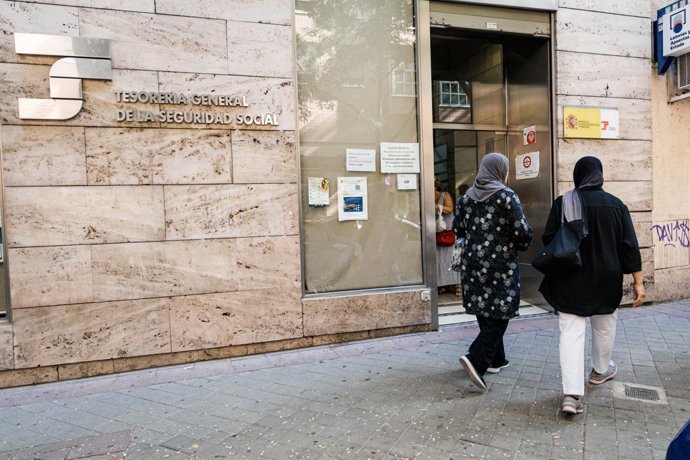 Varias personas migrantes esperan en el exterior de una oficina de la Seguridad Social, a 30 de junio de 2026, en Madrid (España).
