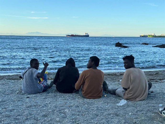 Varios migrantes en la playa del Trampolín, a 3 de agosto de 2026, en Ceuta (España). La ONG ceutí Luna Blanca ha repartido en los últimos días más de 12.000 comidas entre las personas migrantes que accedieron a la ciudad durante la entrada masiva desde M