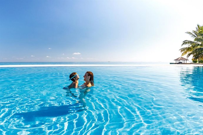 Archivo - Madre e hijo divirtiéndose en la piscina infinita, junto al mar.