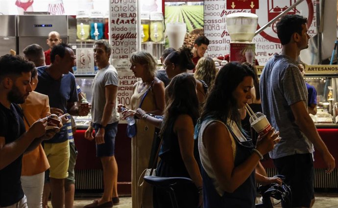 Archivo - Varias personas pasan al lado de una heladería, a 10 de agosto de 2022, en Valencia