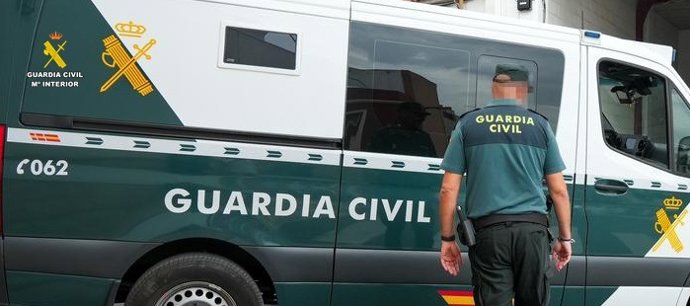 Un agente de la Guardia Civil junto a un vehículo oficial.
