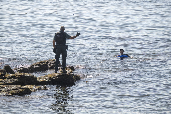 Un guardia civil avisa a una persona que nada en el mar, a 2 de agosto de 2026, en Ceuta (España).