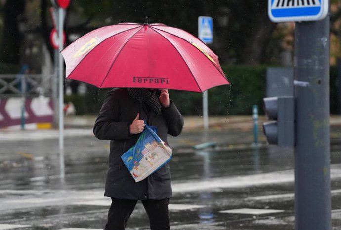 Archivo - Peatones se protegen de la lluvia 