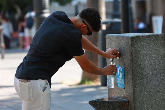 Archivo - Una persona se refresca en una fuente.