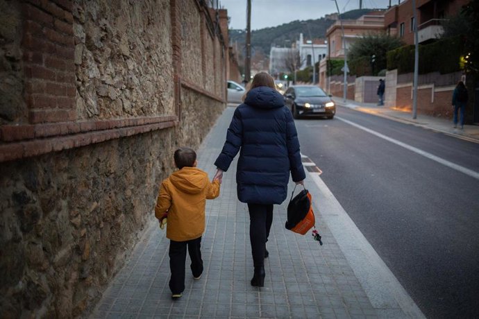 Archivo - Una mujer lleva de la mano a un niño, en una foto de archivo
