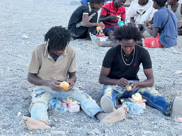 Dos migrantes reciben alimentos básicos, a 3 de agosto de 2026, en Ceuta (España). 