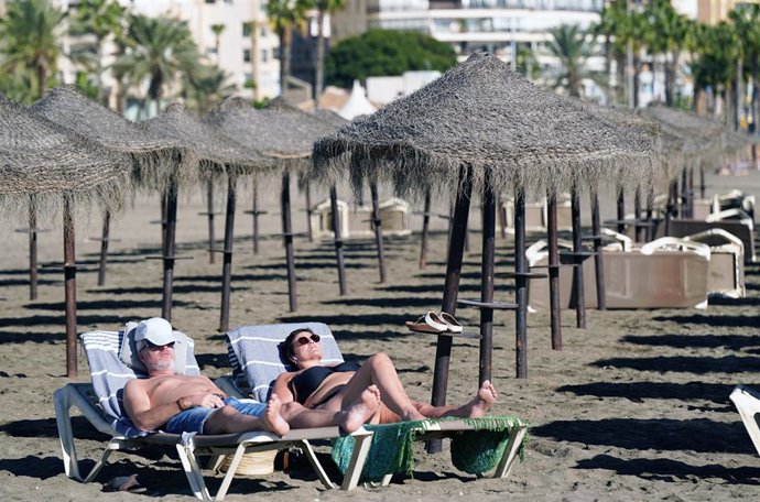 Archivo - Varias personas disfrutan tomando el sol en la playa.