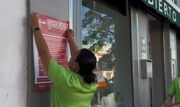 Farmaceutica colocando un cartel con recomendaciones
