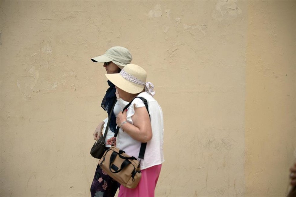 Archivo - Varias personas se protegen del sol.