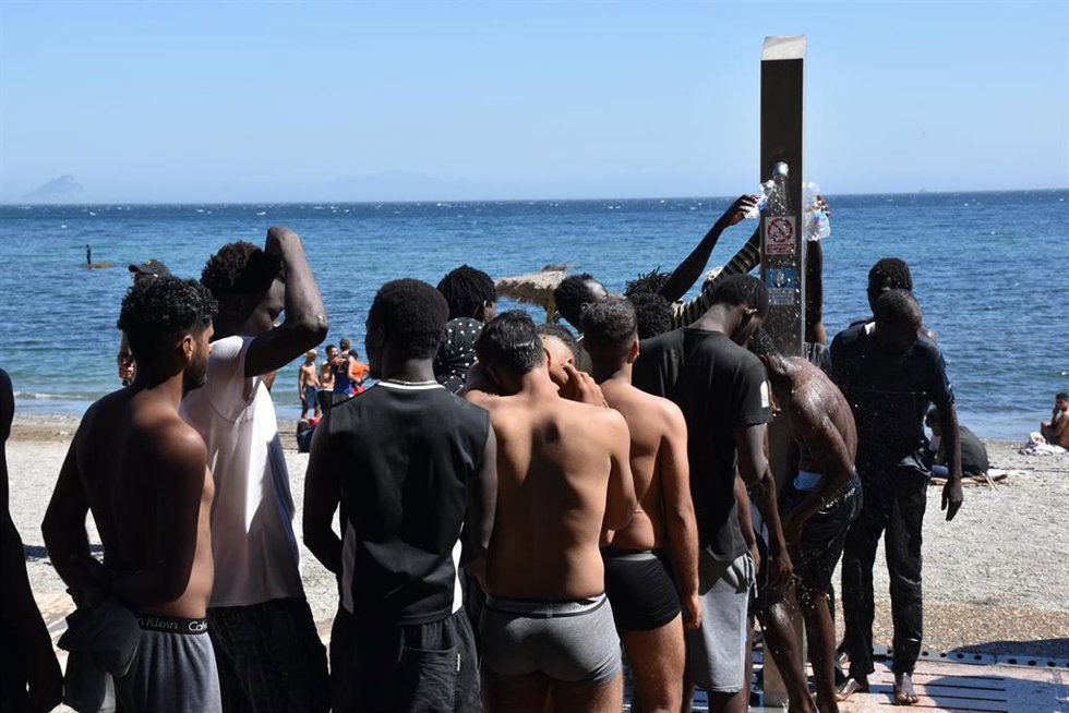 Varias personas se asean en las duchas públicas, en la playa del Trampolín, a 5 de agosto de 2026, en Ceuta (España). La Policía Nacional ha comenzado el proceso de triaje de los migrantes que permanecen en Ceuta, "unos 2.500" según informaciones de la De
