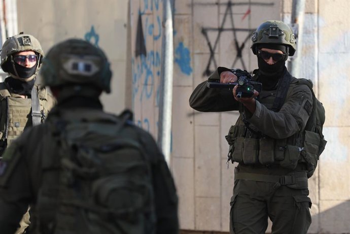 8 de agosto de 2026, Hebron, Palestina, Estado de: HEBRON, Palestina — 8 de agosto de 2026: Uma família palestina permanece sentada dentro de seu veículo após este ter sido parado durante uma incursão de colonos na Cidade Velha de Hebron, enquanto as forç