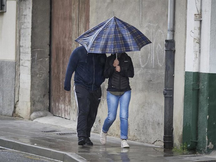 Archivo - Imagen de archivo de dos personas caminando bajo un paraguas