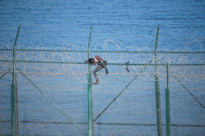 Archivo - Arquivo - Na foto, um dos 153 migrantes que entraram em Ceuta pulando a cerca dupla na primeira incursão em grupo do ano; ele se agarra às cercas de arame farpado.