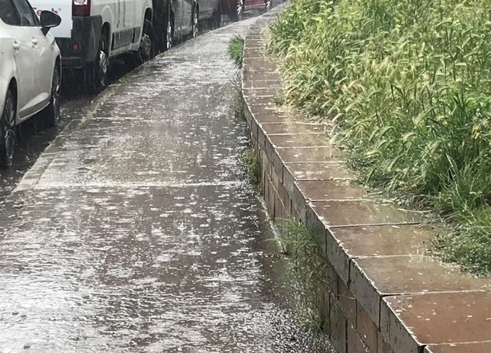 Archivo - Lluvia intensa en una acera y una zona verde