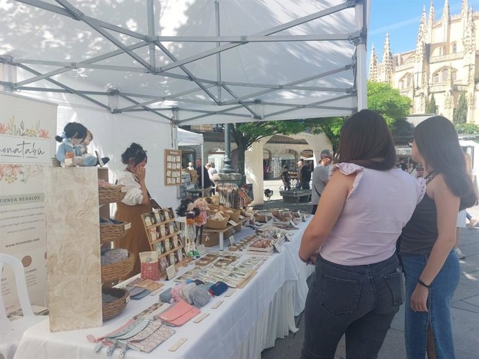 Visitantes de la II Feria del Comercio Segoviano contemplan uno de los puestos