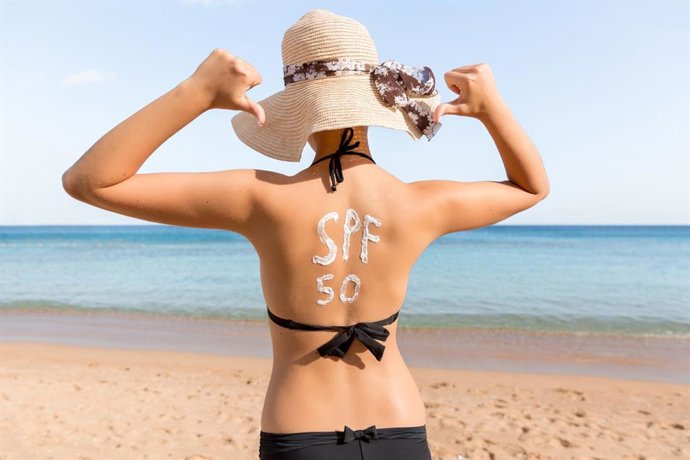 Archivo - Mujer con protector solar en forma de SPF 50 palabra en su espalda tomando el sol.