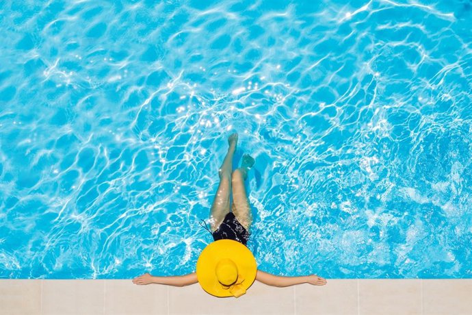 Archivo - Arquivo - Mulher tomando banho de piscina com um chapéu amarelo e maiô.S