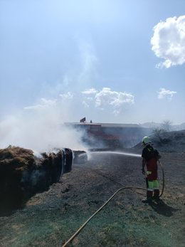 Un bombero trabaja en apagar el fuego en rollos de hierba