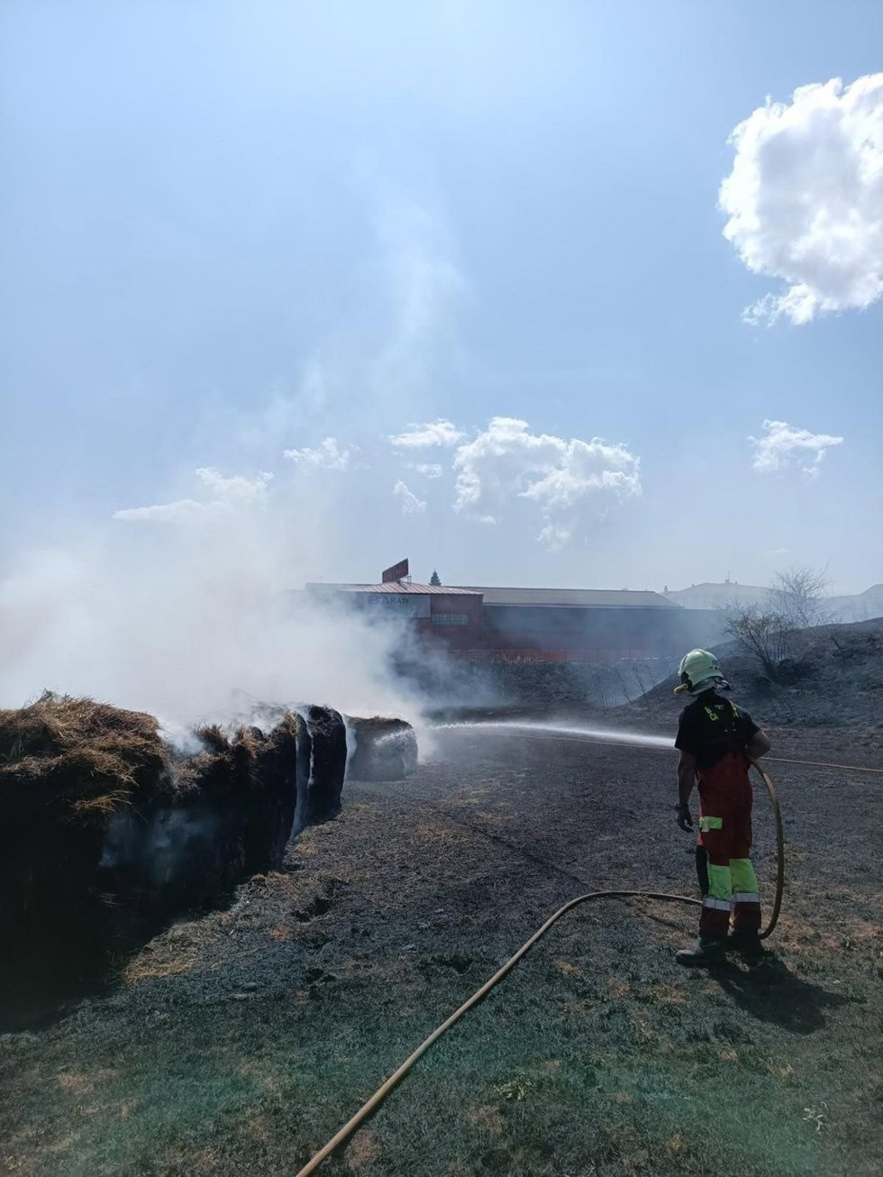 Un bombero trabaja en apagar el fuego en rollos de hierba