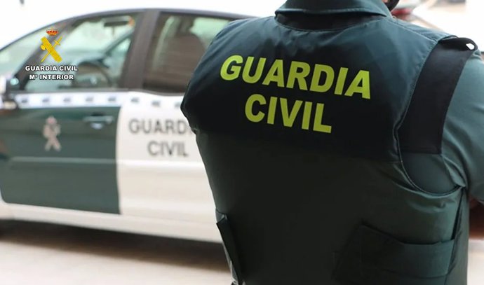 Archivo - Un agente de la Guardia Civil junto a un vehículo oficial.