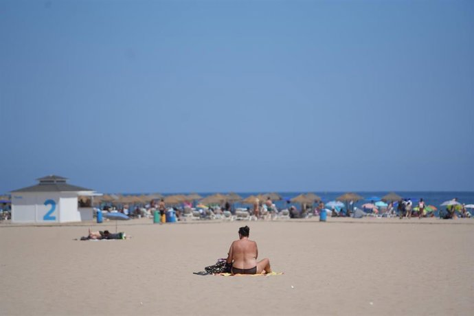 Archivo - Una persona sentada en una toalla en la playa durante la cuarta ola de calor del verano, a 22 de agosto de 2023, en Valencia, Comunidad Valenciana (España).
