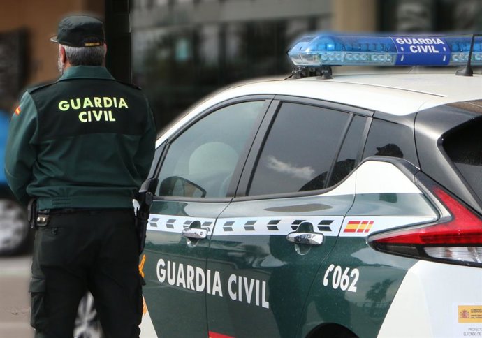 Archivo - Arquivo - Um agente da Guarda Civil, de costas, em pé ao lado de um veículo oficial.
