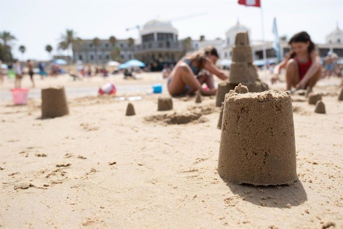 Menores haciendo figuras con la arena en la playa de la Caleta de Cádiz. ARCHIVO.