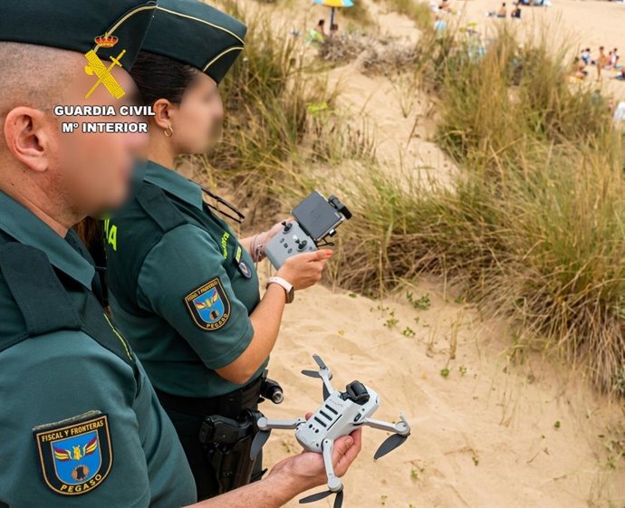 Agentes de la Guardia Civil identifican a un piloto y a un dron durante en un espacio restringido de observación del eclipse en la playa de Valdearenas