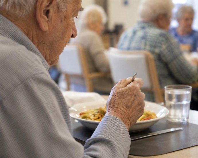 Imagen de archivo de una persona mayor comiendo.
