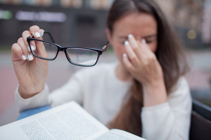 Archivo - Closeup portrait of attractive female with eyeglasses in hand. Poor young girl has issues with vision. She rubs her nose and eyes out of fatigue. A student tired to study and read books