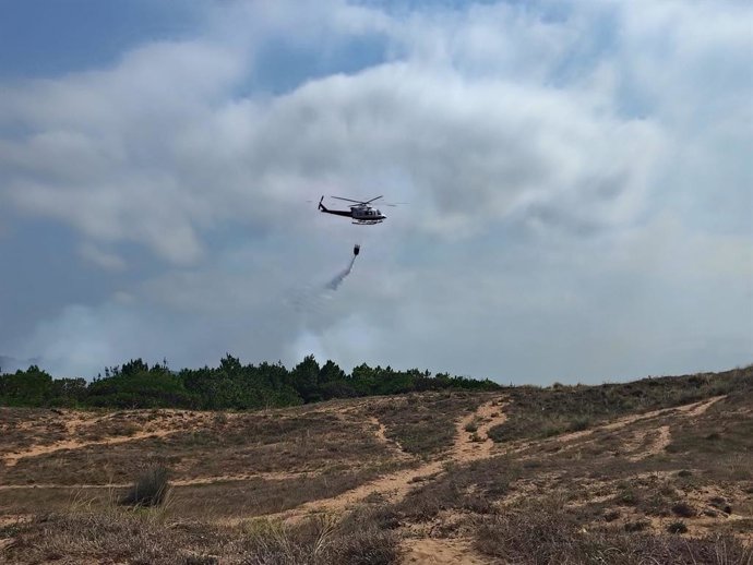 O helicóptero e os bombeiros do governo da Cantábria estão atuando no incêndio nos pinheiros de Liencres