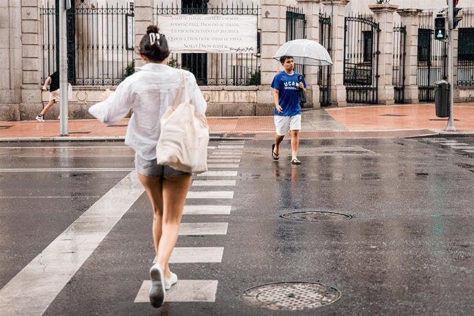 Archivo - Varias personas pasean bajo la lluvia, a 25 de junio de 2026, en Madrid (España). 