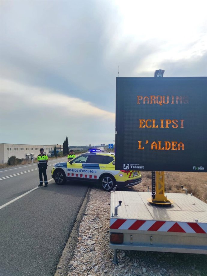 Agentes de los Mossos d'Esquadra controlan el tráfico cerca de un aparcamiento habilitado para la observación del eclipse en L'Aldea (Tarragona)