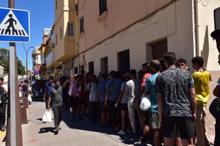 Varias personas hacen cola en un punto de atención humanitaria, a 5 de agosto de 2026, en Ceuta (España). 