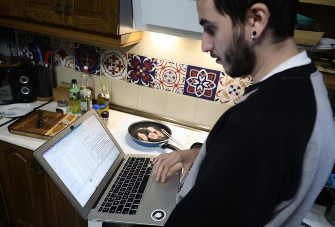 Archivo - Una persona teletrabaja en la cocina de su domicilio.