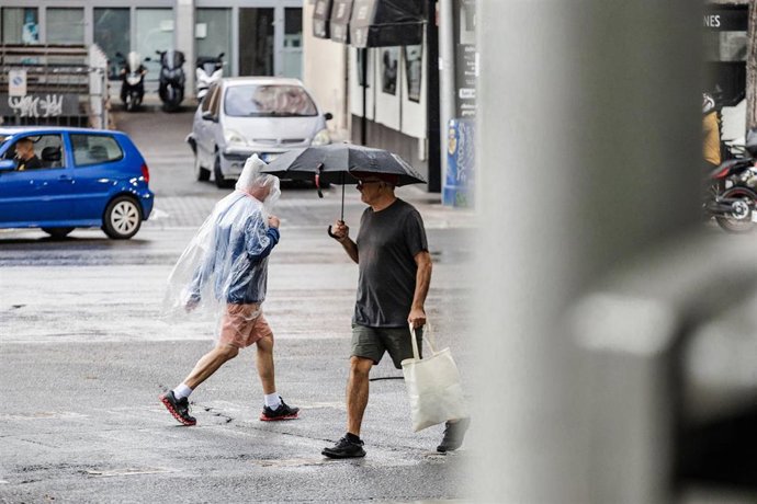 Archivo - Dos personas caminan bajo la lluvia, en Madrid (España). 