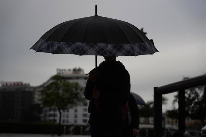 Archivo - Peatones se protegen de la lluvia bajo sus paraguas, durante el paso de la borrasca Joseph. A 27 de enero del 2026 en Sevilla (Andalucía, España).