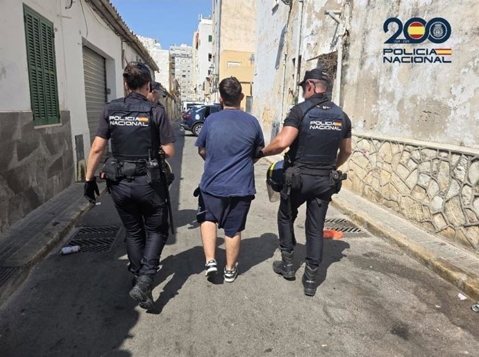 Dos agentes escoltan a uno de los tres detenidos.