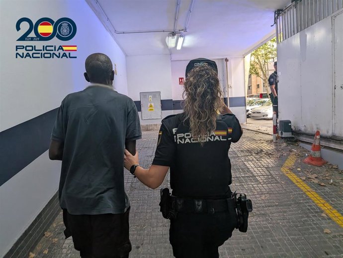 El detenido, de espaldas, escoltado por una agente de la Policía Nacional.