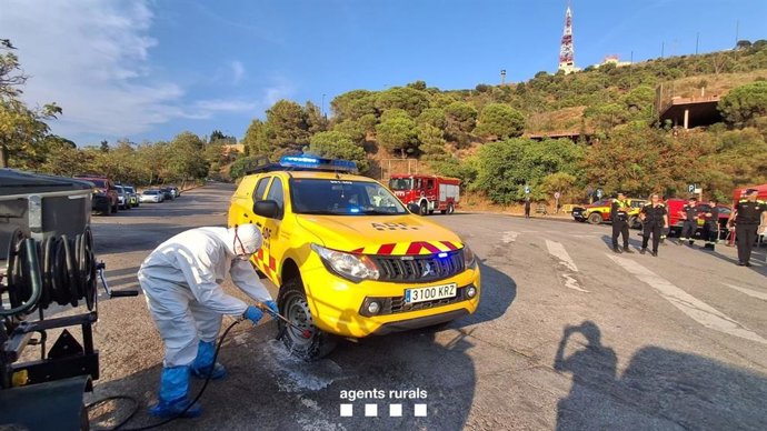 Una persona desinfecta un vehículo de las Agrupaciones de Defensa Forestal (ADF) durante el incendio de Collserola (Barcelona)