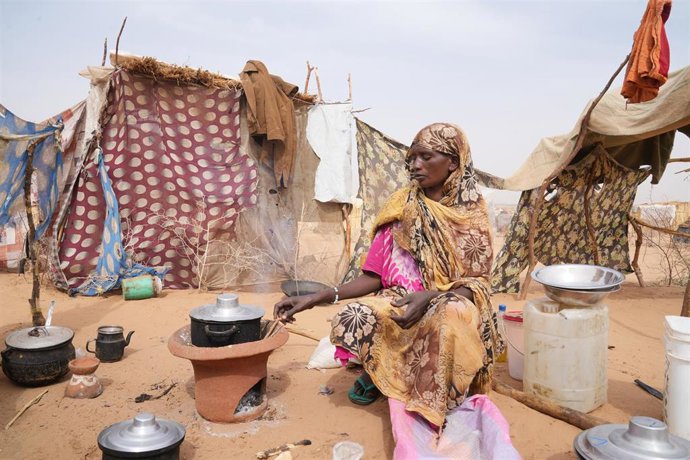 Archivo - Una mujer prepara la comida frente a una tienda de campaña desgastada en un campamento de desplazados cerca de la localidad fronteriza de Al-Tina, en el oeste de Sudán.