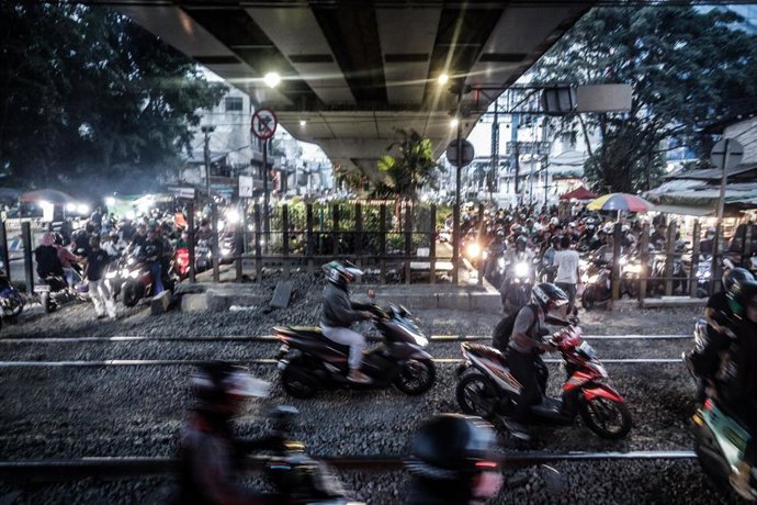 Archivo -  Un motociclista espera a que pase un tren en un paso a nivel situado en la zona de Roxy, en Gambir, Yakarta (Indonesia)