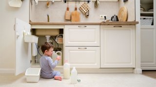 Archivo - Un niño está jugando con productos químicos de limpieza debajo del fregadero de la cocina. El bebé sostiene biberones con detergente. Niño de aproximadamente dos años (un año nueve meses)