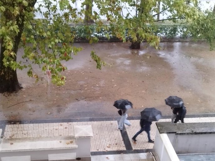 Archivo - Varias personas pasean bajo la intensa lluvia en San Sebastián